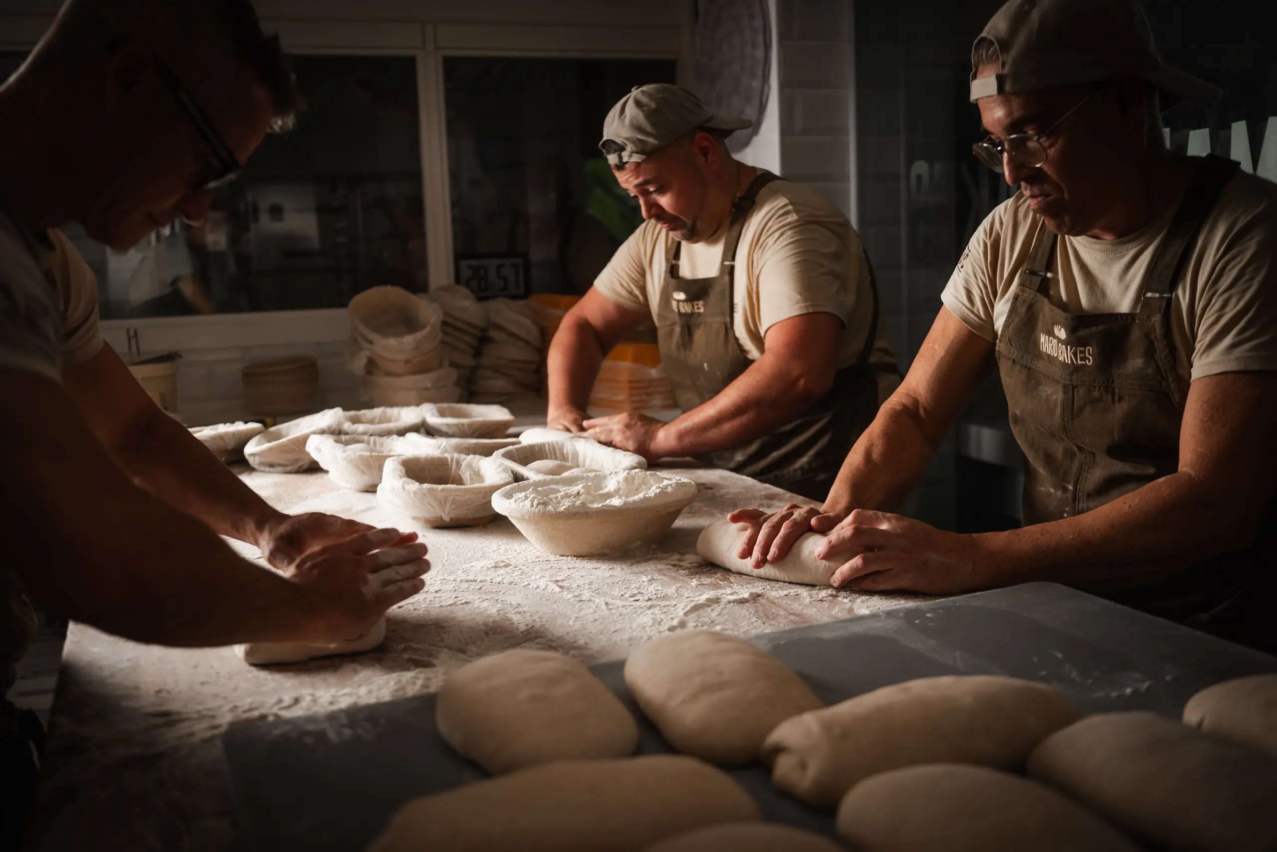 El equipo formando hogazas alrededor de la mesa del obrador