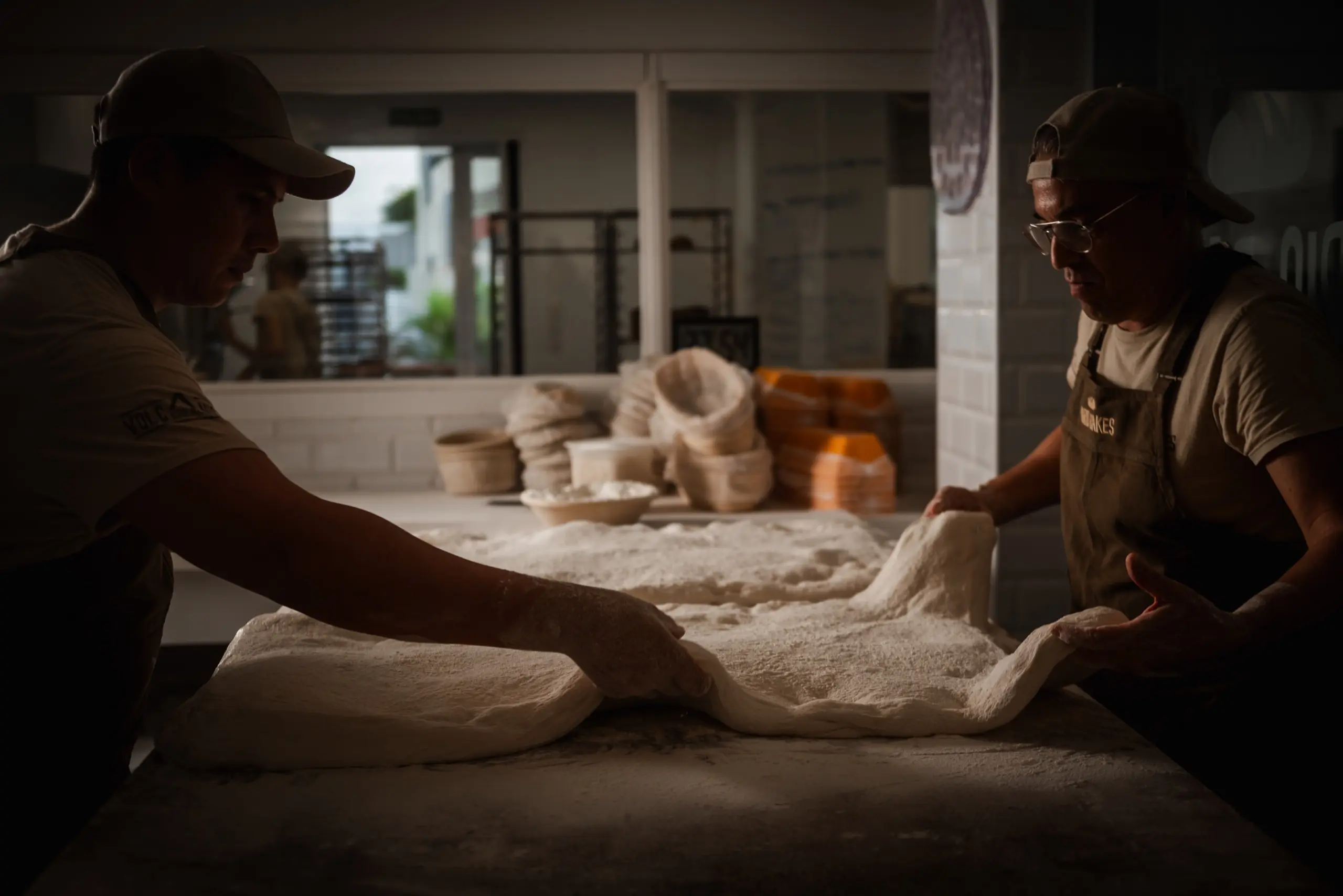 Dos panaderos estirando la masa durante la noche